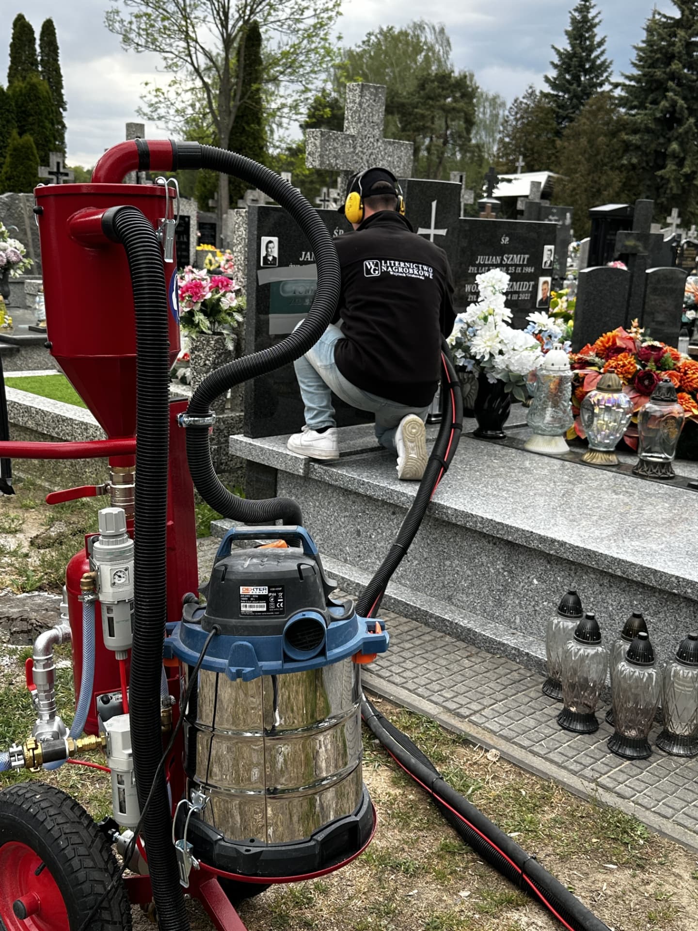 Praca przy nagrobku na cmentarzu, na pierwszym planie maszyna do piaskowania